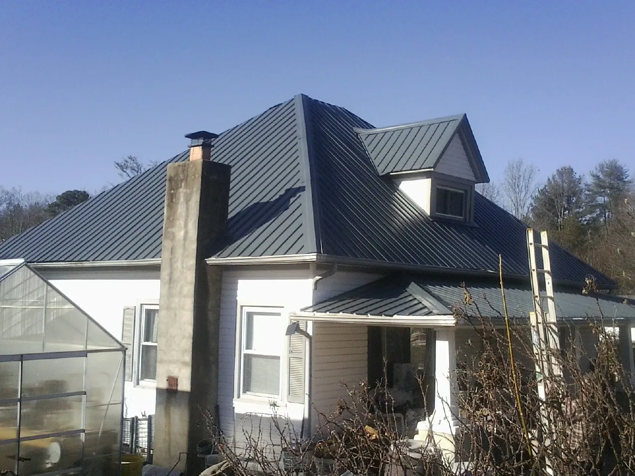 Dark blue standing seam metal roof on a white farmhouse with dormer — Slate & Tile Roof Repair by Roofing Brothers in Washington Depot