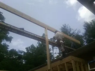 Carpenter setting a ridge beam over a new addition frame — Ice Dam Removal by Roofing Brothers in Washington Depot
