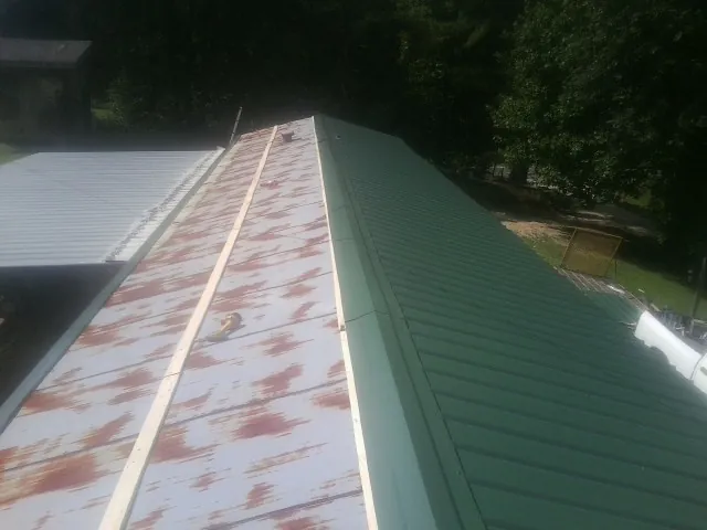Old rusted panels beside newly installed green metal roofing — Wind Damage Roof Repair by Roofing Brothers in Washington Depot