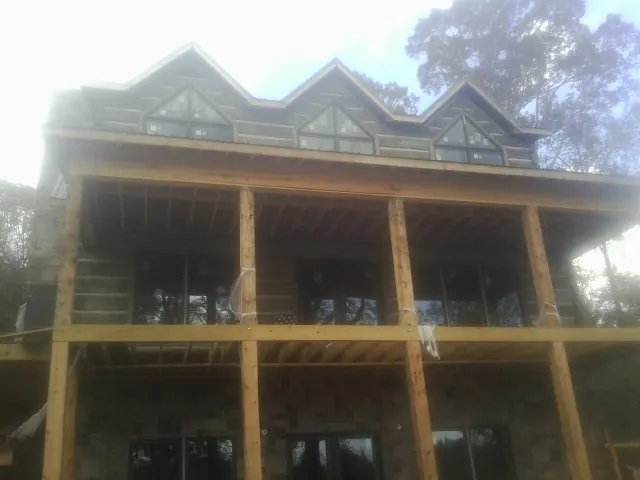 Dormers and porch framing on a large log home under construction — Roof Coating work by our crew in Washington Depot