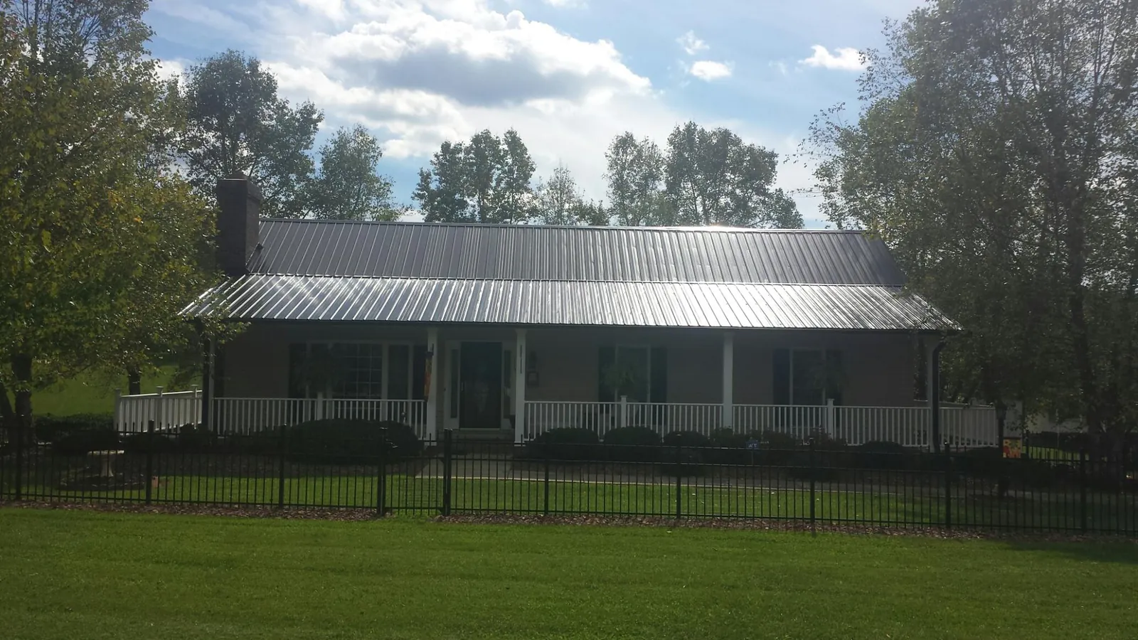 Gray metal roof on a brick ranch with a full width front porch — Gutter Guard Installation work by our crew in Washington Depot