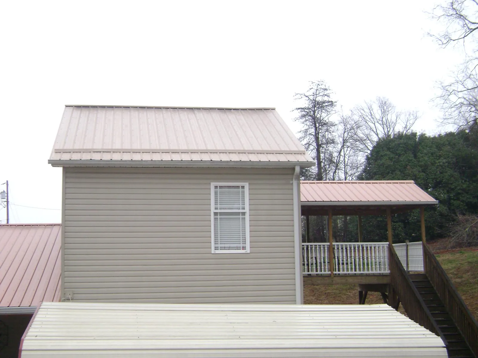 Tan metal roofs on a two story addition and attached porch, from a Roof Replacement job in Washington Depot