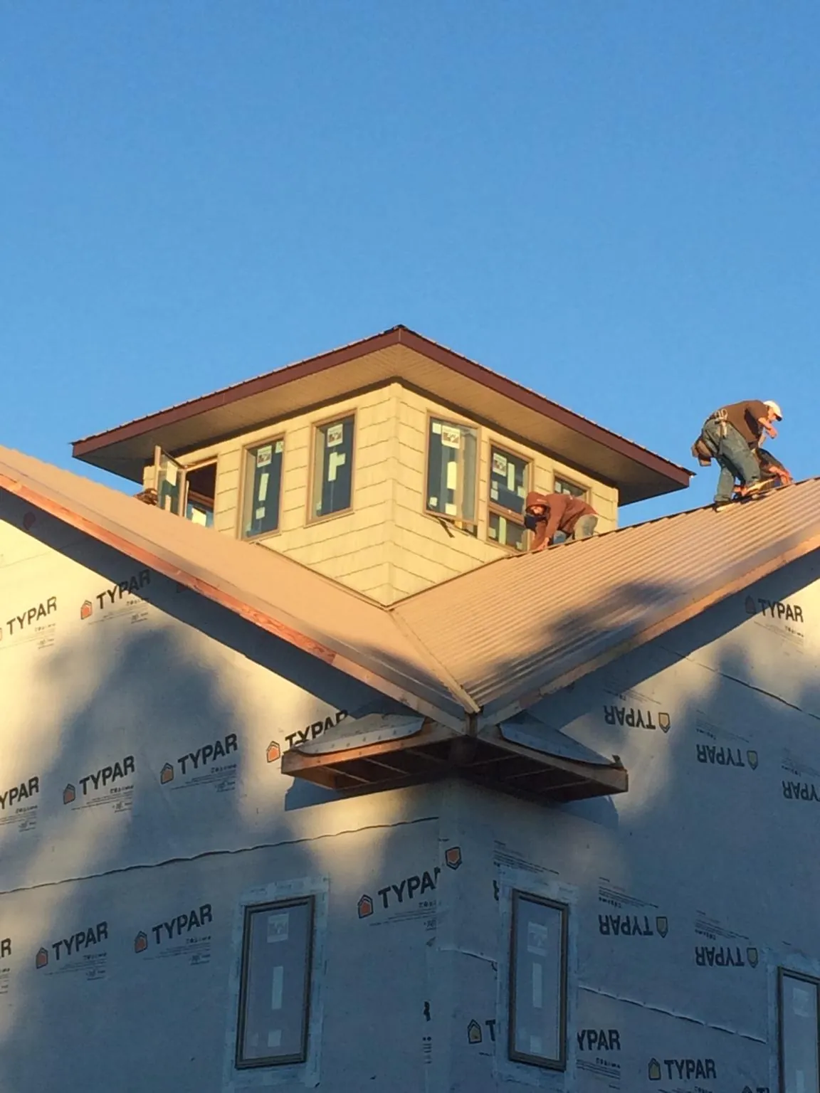 Roofers working around a rooftop cupola on a new metal roof at sunset — Roof Waterproofing in Washington Depot by Roofing Brothers